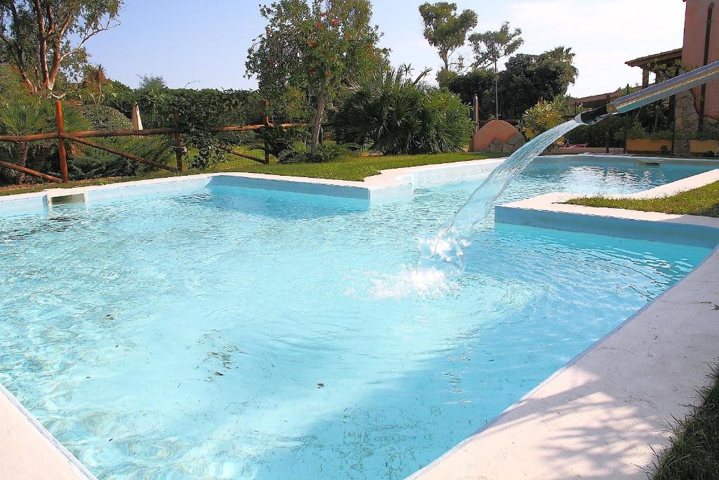 ein Schwimmbad mit einem Brunnen in der Mitte in der Unterkunft Villaggio Piscina Rei in Monte Nai