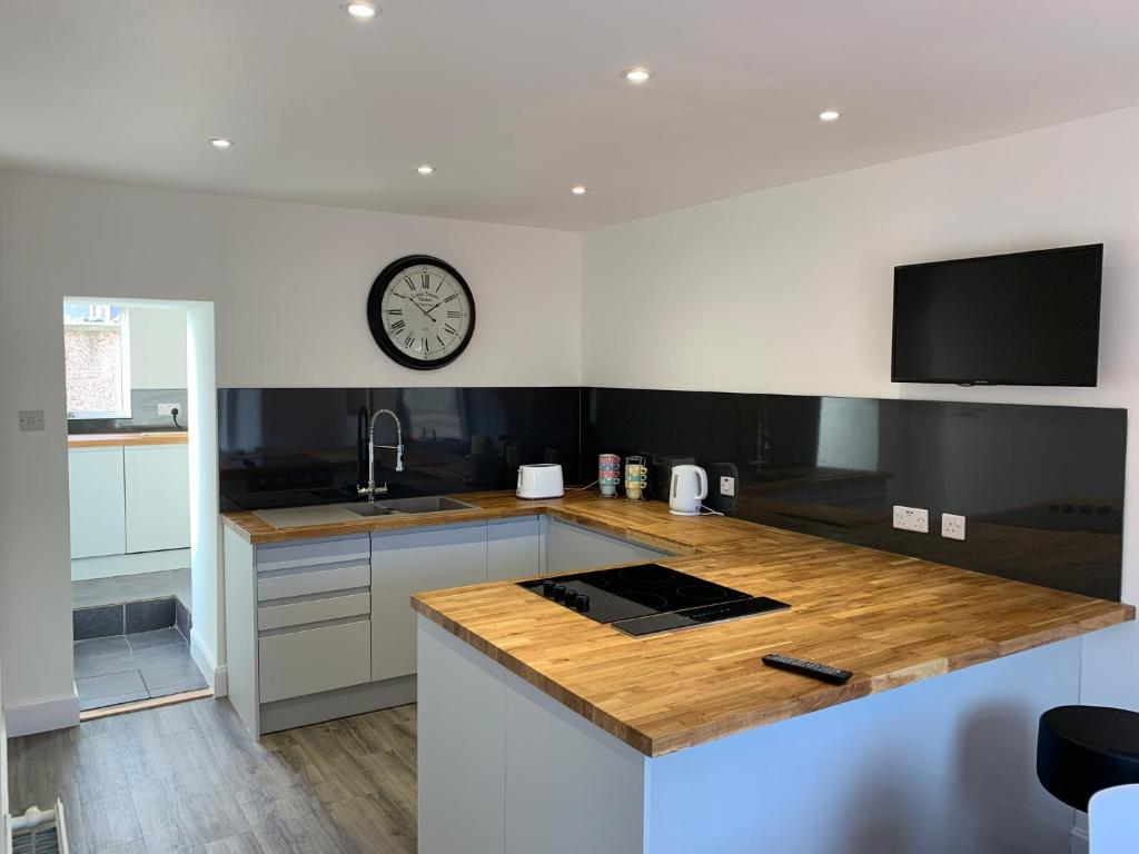 a kitchen with a counter and a clock on the wall at Serviced Accommodation Moray Lossiemouth in Lossiemouth