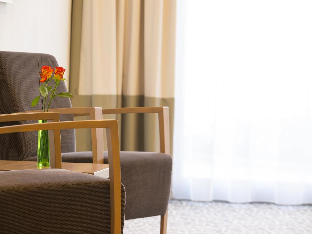 um vaso de flores sentado numa mesa ao lado de uma cadeira em Holiday Inn Express Nürnberg-Schwabach em Schwabach