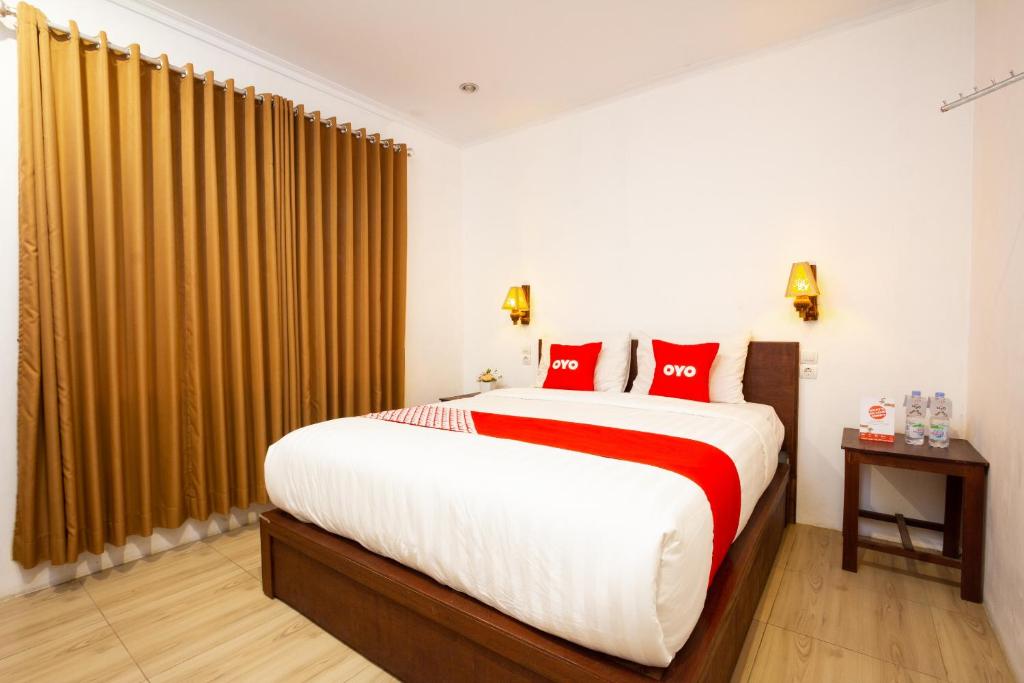 a bedroom with a large bed with red pillows at OYO 2068 Abhaya Mudra Homestay in Magelang