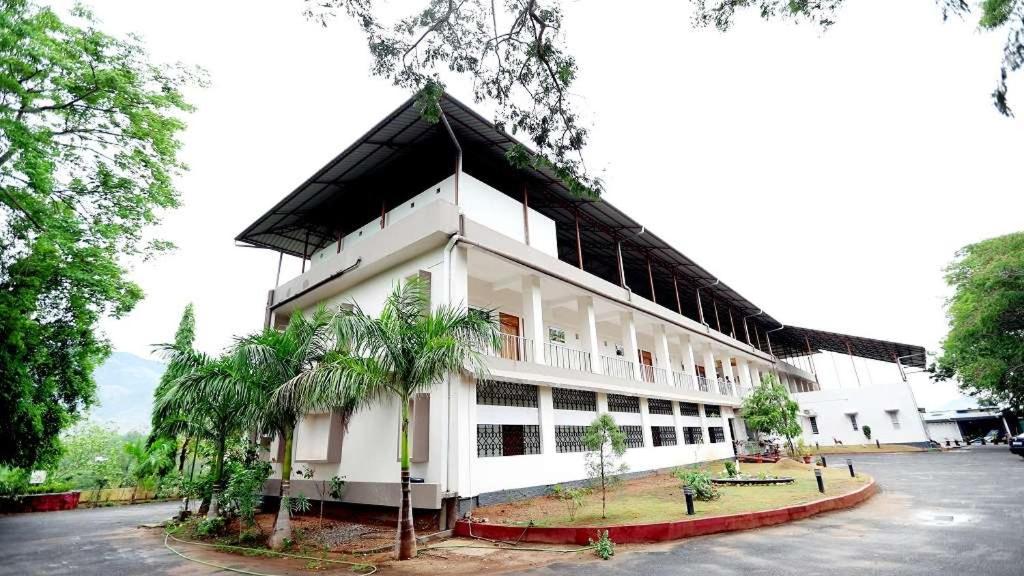 a large white building with palm trees in front of it at KTDC Garden House in Palakkad