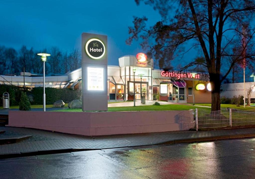 un cartel en frente de una gasolinera por la noche en Hotel Göttingen-West, en Rosdorf