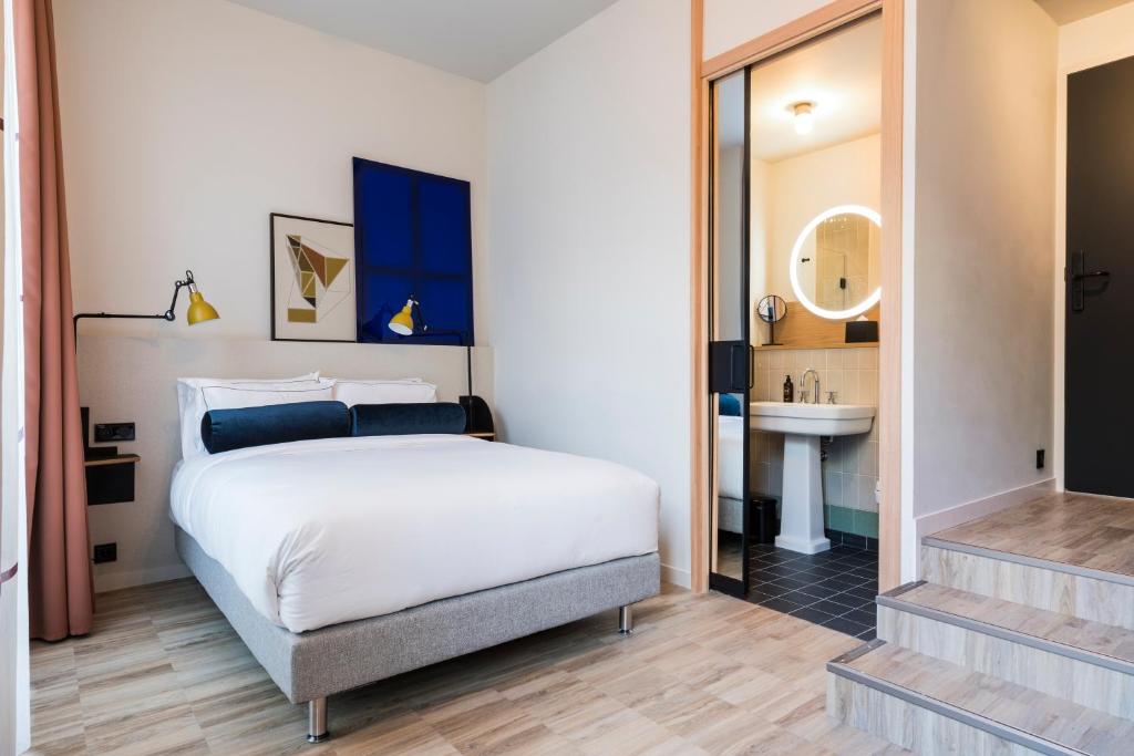 a bedroom with a white bed and a sink at Le Grand Quartier in Paris