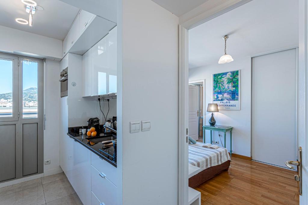 une cuisine avec des armoires blanches et un lit dans une chambre dans l'établissement PALAIS MED - Palais Méditerranéen - Panoramic view, à Nice