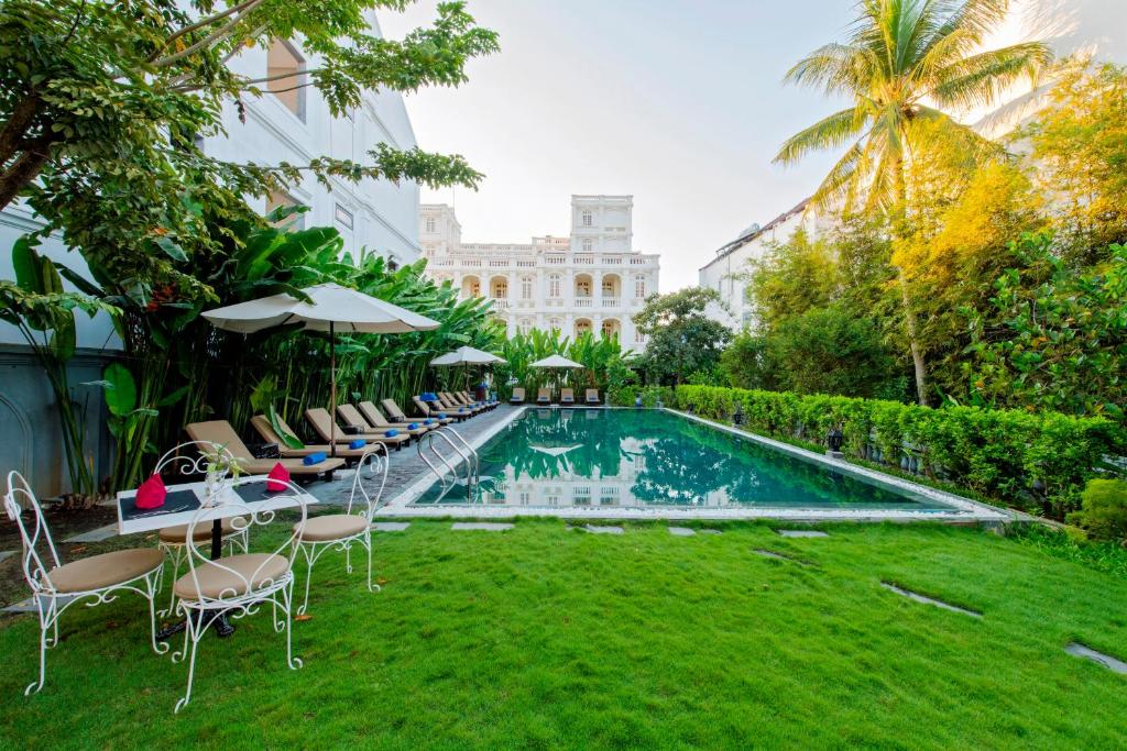 a swimming pool with chairs and a lawn and a building at Hoi An Garden Palace & Spa in Hoi An