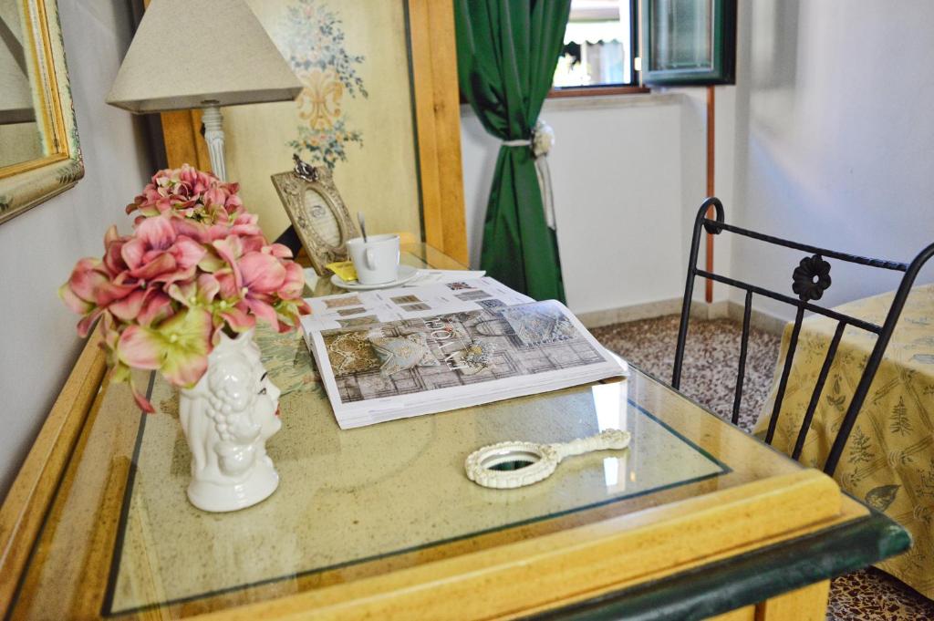 a glass table with a vase with flowers and a magazine at Hotel Victoria in Taormina