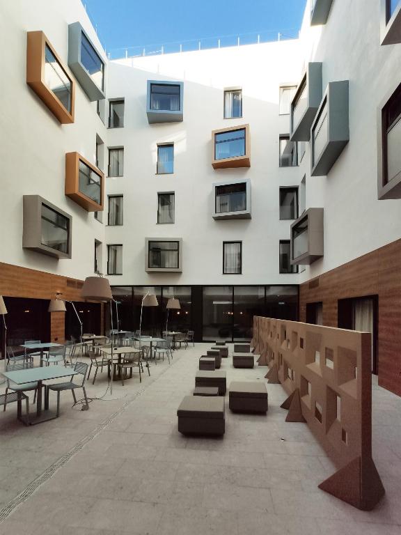 un edificio con mesas y sillas en un patio en Hotel Macià Sevilla Kubb, en Sevilla