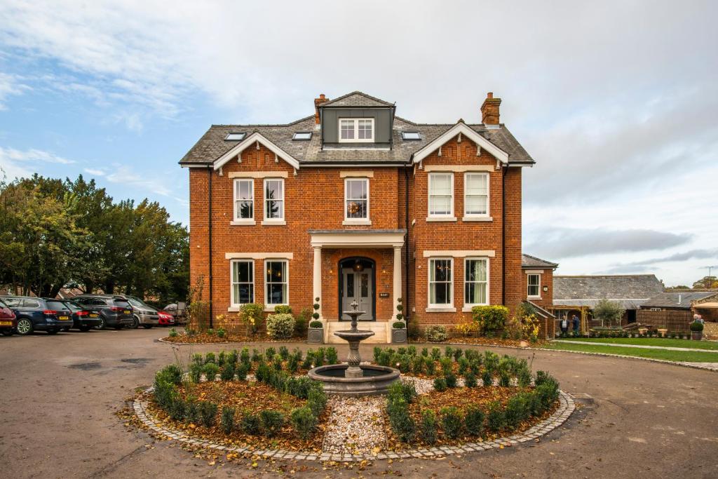 una casa de ladrillo con una fuente delante de ella en The Lodge Duxford, en Duxford