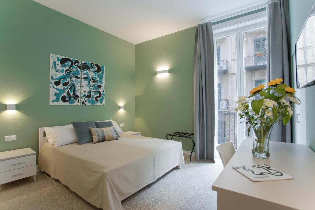 um quarto com uma cama e uma mesa com um vaso de flores em Donna Isa B&B em Palermo