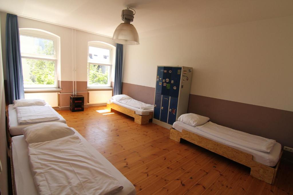 a room with three beds and two windows at 36 Rooms Hostel Berlin Kreuzberg in Berlin