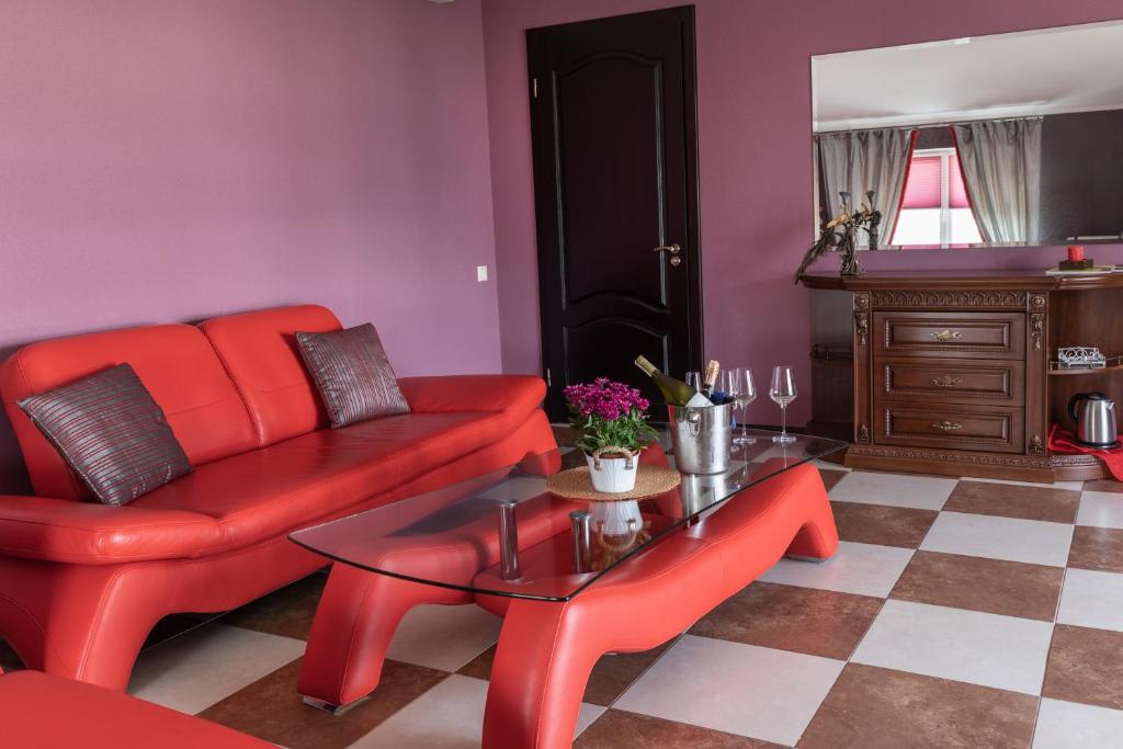 a living room with a red couch and a table at Dergachov Guest House in Zhukovtsy
