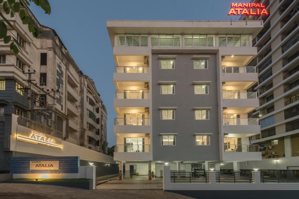 een hoog wit gebouw met een bord erop bij Manipal Atalia Service Apartments in Manipala