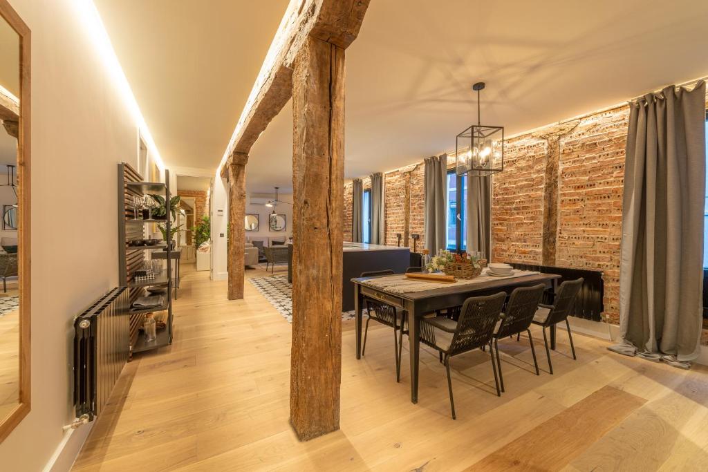 een eetkamer met een tafel en stoelen en een bakstenen muur bij New Soho AC by Staynnapartments in Bilbao