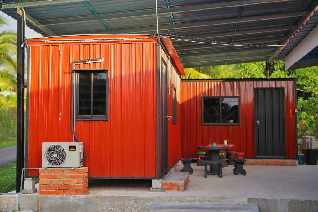 巴東勿剎的住宿－Padang Besar Red Cabin Homestay，橙色集装箱,前面有桌子