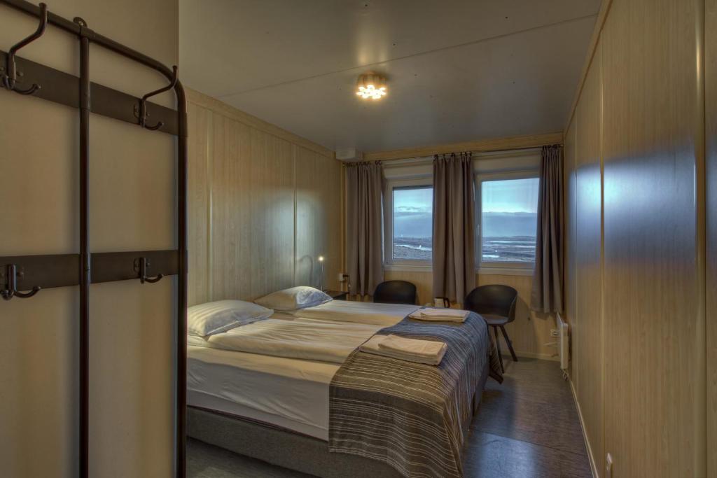 a bedroom with a bed with two chairs and a window at Vikingcafe in Höfn