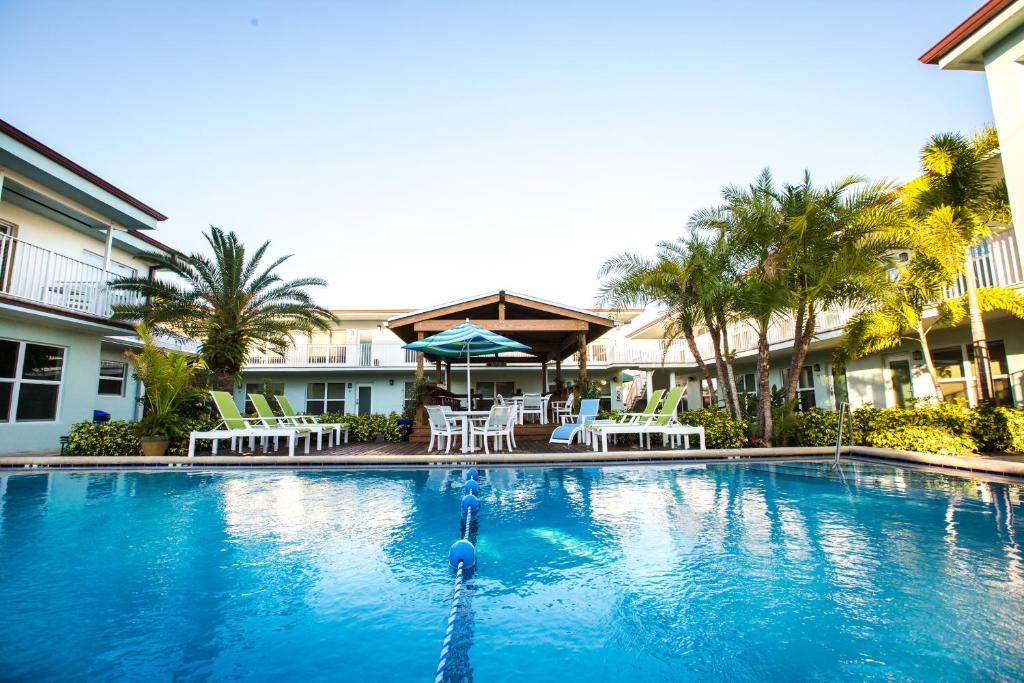 a swimming pool with chairs and umbrellas at a resort at Sun Dek Beach House in Boynton Beach