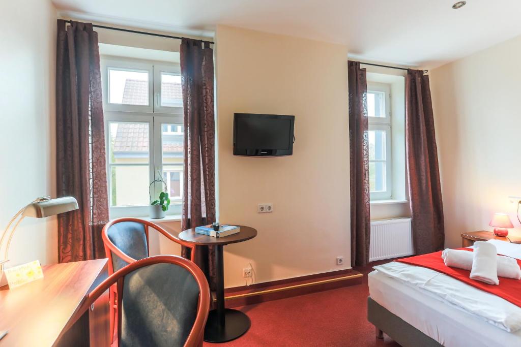 a hotel room with a bed and a desk and a tv at Hotel &amp; Restaurant ,,Zur Alten Oder&quot; in Frankfurt-Oder in Frankfurt Oder
