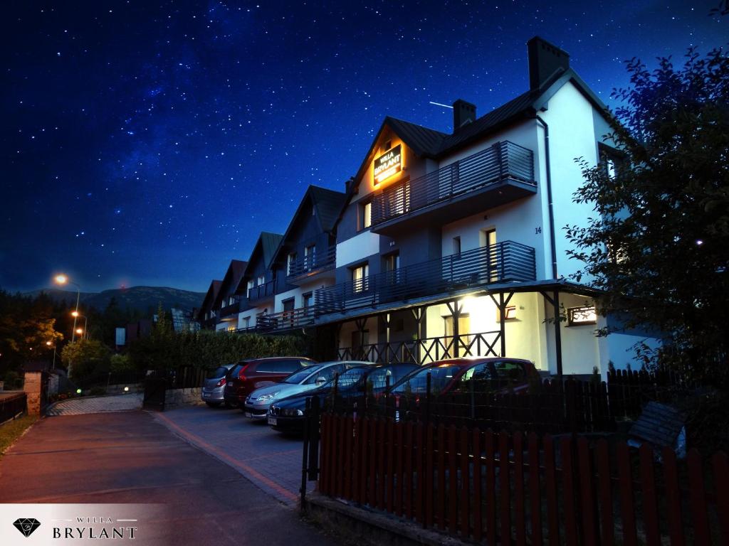 a building with cars parked in a parking lot at night at Willa Brylant in Szklarska Poręba