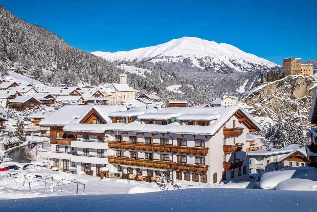 a hotel in the snow with a mountain in the background at Hotel Puint in Ladis