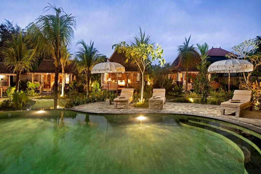 a swimming pool in a resort with chairs and umbrellas at Green Space Villa in Ubud