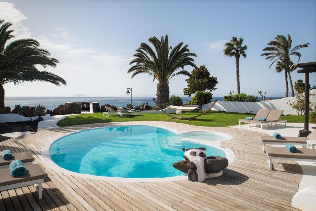 a beach with a pool, chairs, and a pool table at Kamezí Boutique Hotel Villas in Playa Blanca
