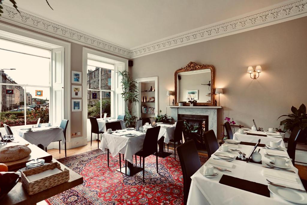 un restaurante con mesas y sillas blancas y un espejo en Sheridan Guest House, en Edimburgo
