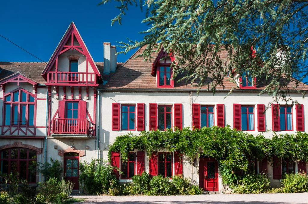 una gran casa blanca con persianas rojas en Au Puy Des Vérités en Lapalisse