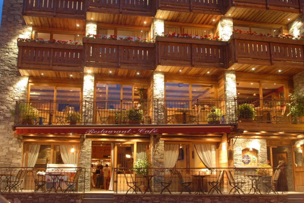 een gebouw met tafels en stoelen ervoor bij Hotel Le Monal in Sainte-Foy-Tarentaise