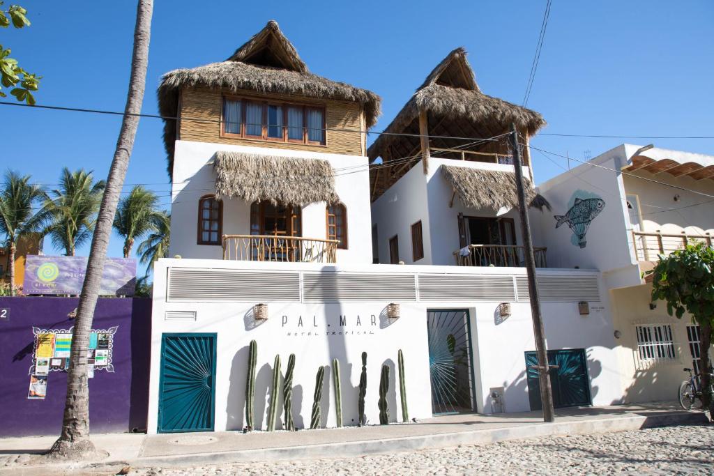 a white building with a thatched roof at PAL.MAR Hotel Tropical in San Francisco