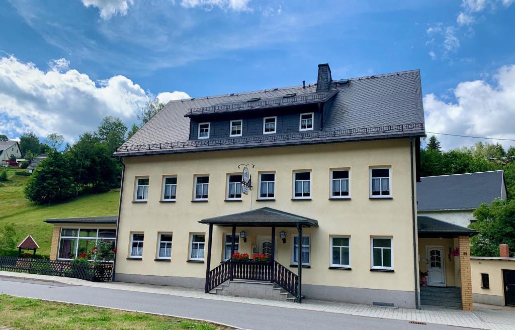 a large white house with a black roof at Pension Weiberwirtschaft in Pobershau in Pobershau