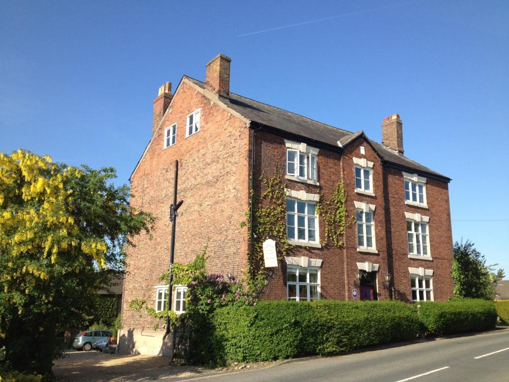 an old red brick building with ivy on it at Pickmere Country House in Pickmere