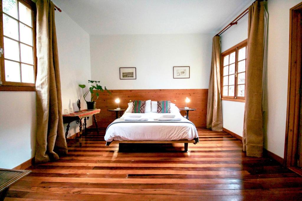 um quarto com uma cama e pisos e janelas em madeira em Casa California Guesthouse em Valparaíso