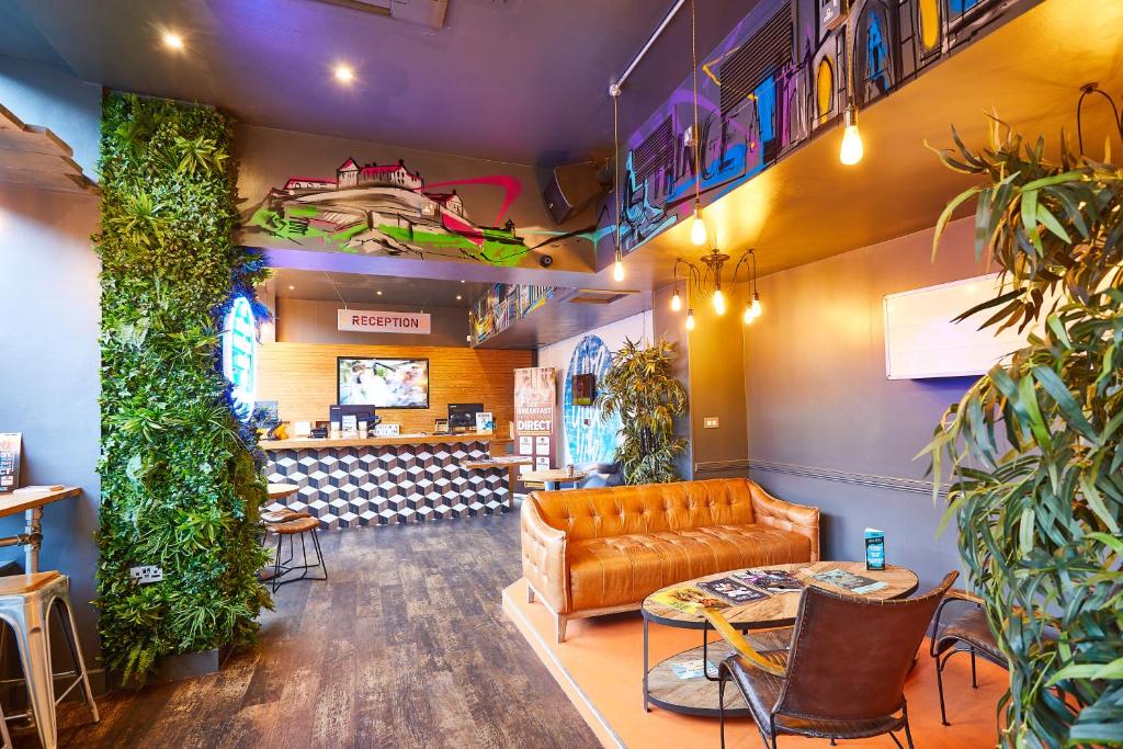 a waiting room with a leather couch and plants at St Christopher's Edinburgh Old Town in Edinburgh