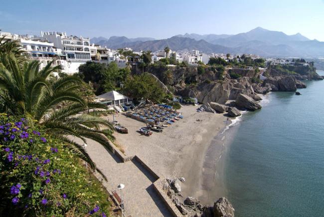 a beach with a group of people sitting on the beach at Nerja Villas-Capistrano in Nerja