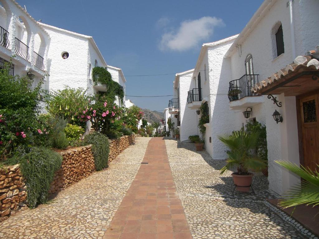 a narrow street with white buildings and plants at Nerja Villas-Capistrano in Nerja