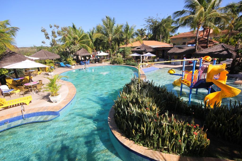 a beach with a pool, chairs, tables, and umbrellas at Thermas Park Resort & SPA by Hot Beach in Olímpia