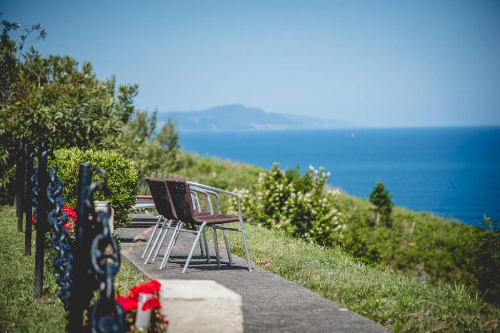 un grupo de sillas sentadas en un camino cerca del océano en Gure ametsa, en Getaria