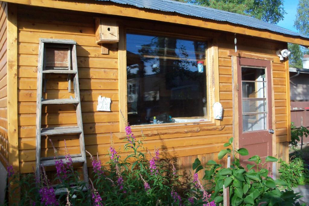 Cabaña de madera con ventana y escalera en Cabine, Home Sweet Home, en Whitehorse