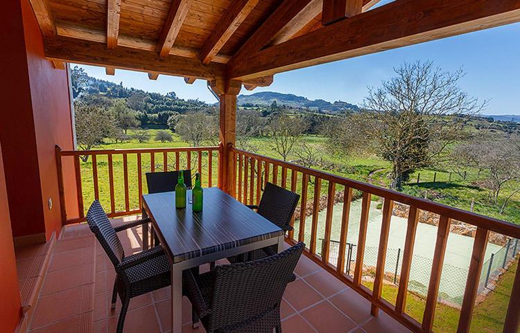 a wooden deck with a table and chairs on a balcony at Apartamentos Vega Rodiles el campu in Villaviciosa