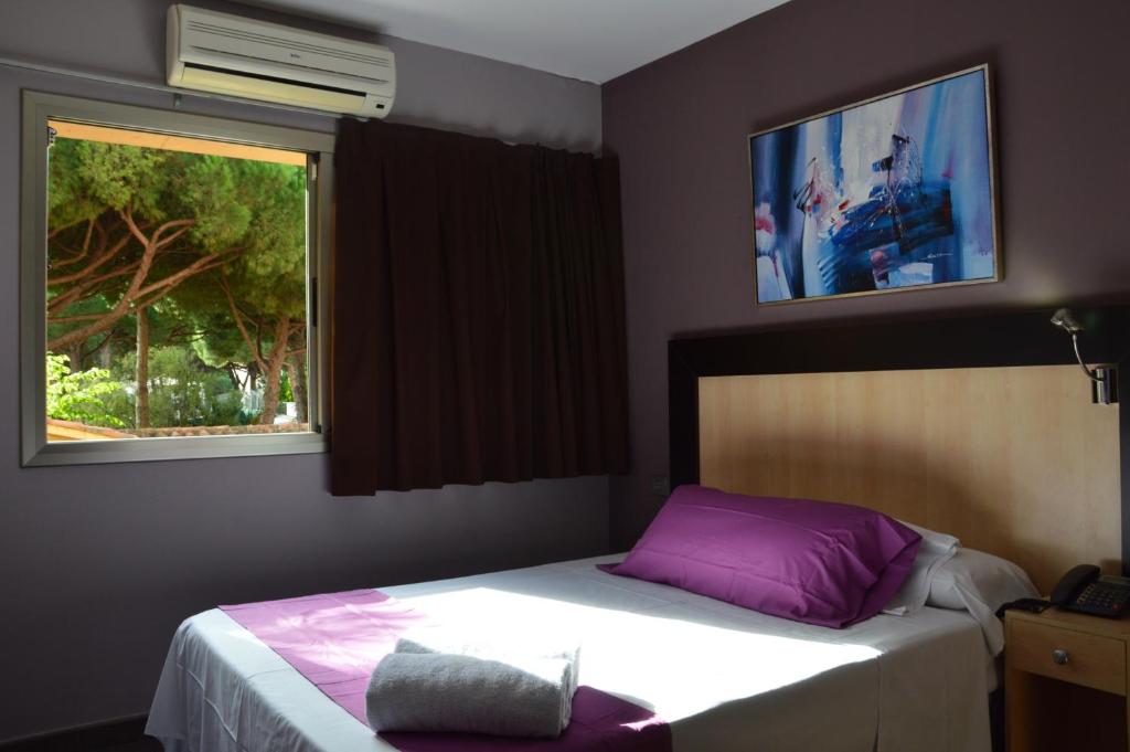 a bedroom with a bed with purple pillows and a window at Hotel 170 in Castelldefels