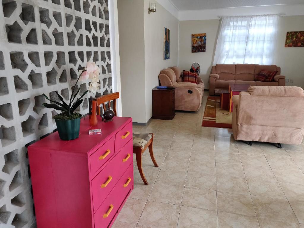 a living room with a pink dresser with a plant on it at Tropical Villa in Roseau