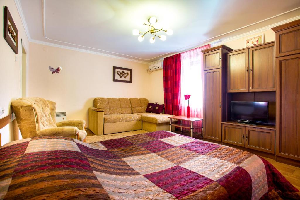 um quarto com uma cama, um sofá e uma televisão em Central Park Apartment in the City Center em Kherson