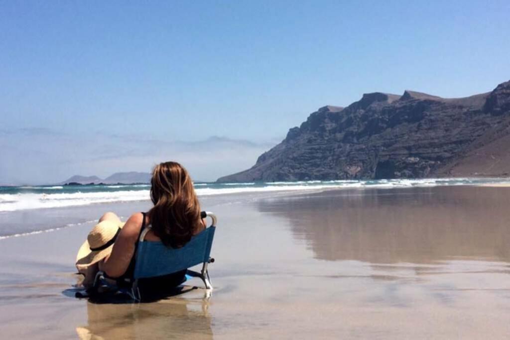 a woman sitting on a chair on the beach at Lanzarote Famara Beach in Famara
