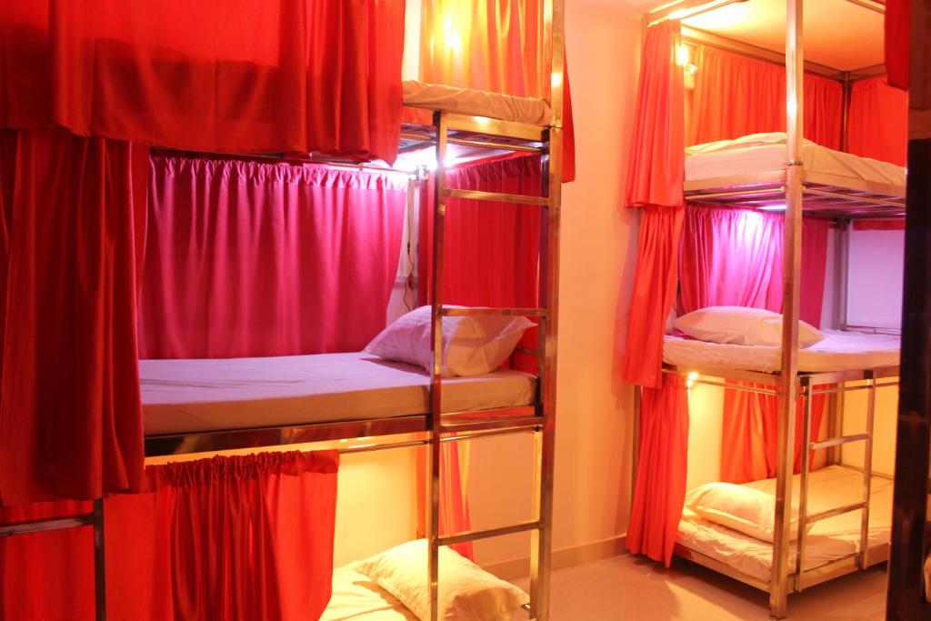 a room with four bunk beds with red curtains at Sunset Backpackers Hostel in Orchha