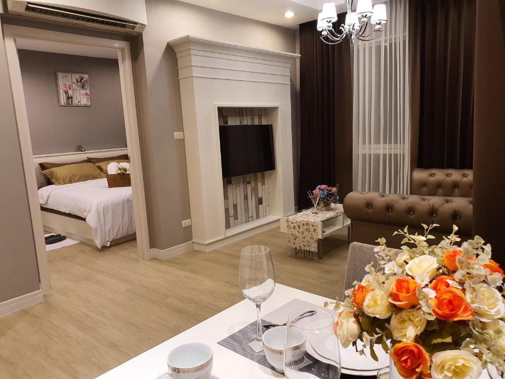 a living room with a bed and a table with flowers at Exclusive Garden View 1 bedroom suite @Patio Bangsaen in Bangsaen