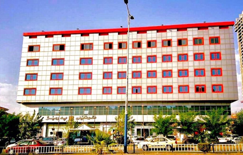 a large white building with a red roof at Prizh Hotel in As Sulaymānīyah