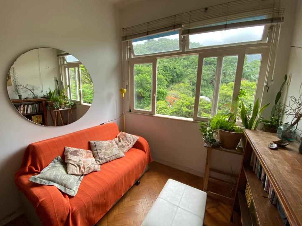 sala de estar con sofá naranja y espejo en Vista pro verde, en Río de Janeiro