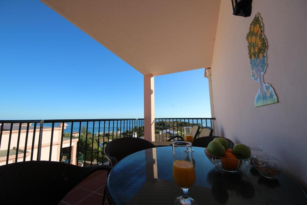 a table with a glass of orange juice on a balcony at Brisa Mar para 4 com piscina e WiFi in Luz