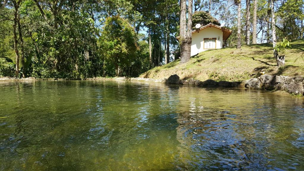 una casa sentada en la cima de una colina junto a un río en Cabanas da Fazenda, en Visconde De Maua