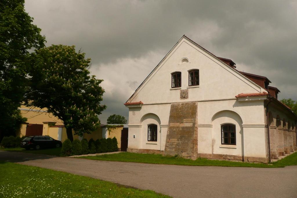 una vieja iglesia blanca con un cielo nublado en el fondo en Statek Chmelovice en Chmelovice